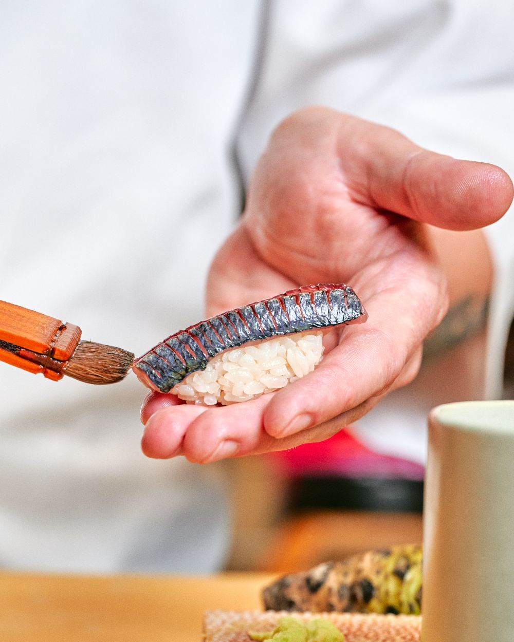 Le chef façonne un nigiri et le badigeonne de sauce au pinceau